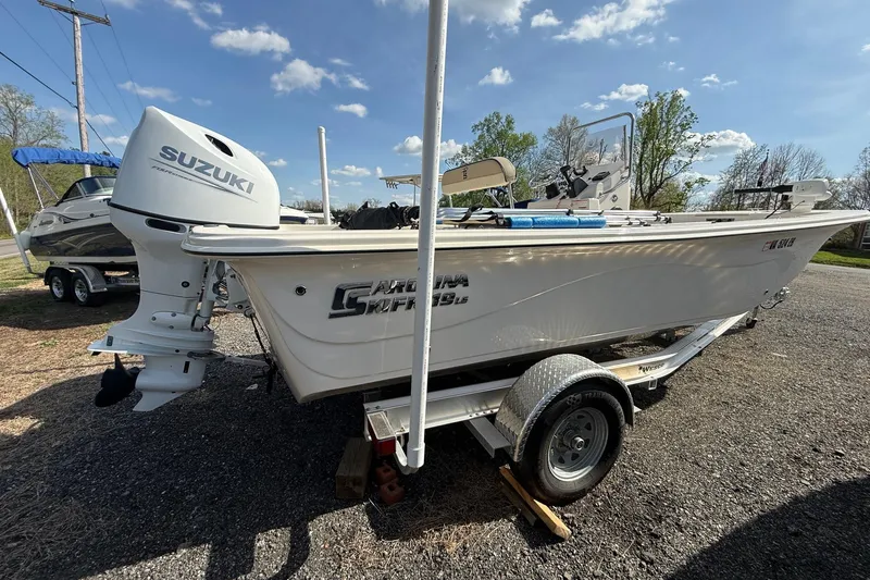 Slide: The Image of 2023 Carolina Skiff 19 LS boat with Suzuki outboard motor on a trailer, parked outdoors. - 10