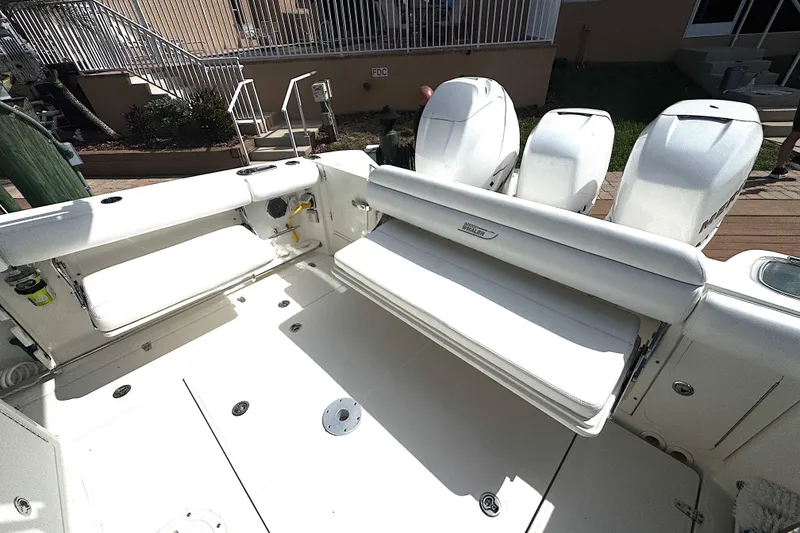 Slide: The Image of 2014 Boston Whaler 350 Outrage boat interior with side seating and back seating and triple outboard engines. - 20