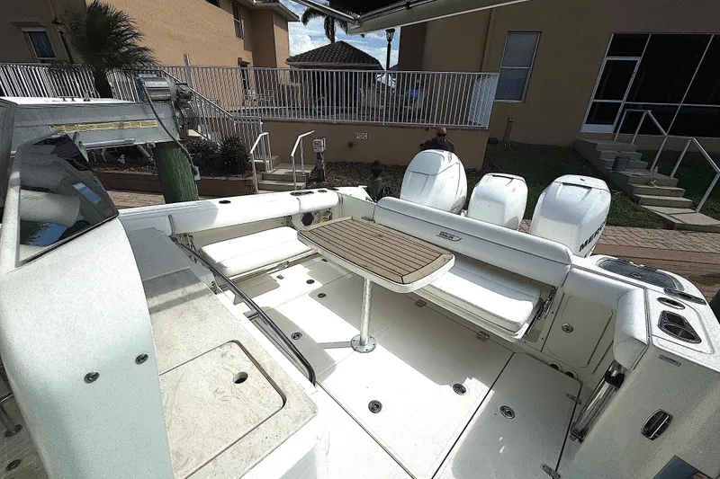Slide: The Image of 2014 Boston Whaler 350 Outrage boat interior with  side and rear seating with table, docked near a house. - 39