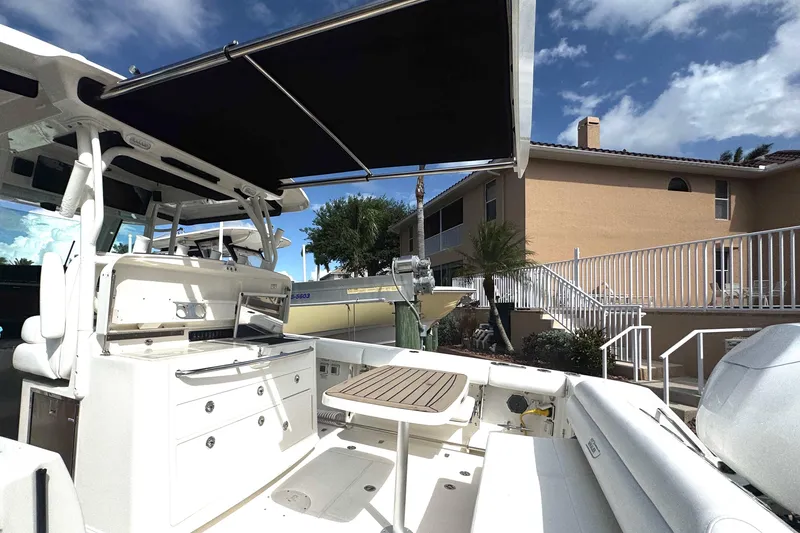 Slide: The Image of 2014 Boston Whaler 350 Outrage boat interior with seating and canopy, docked near a house. - 41