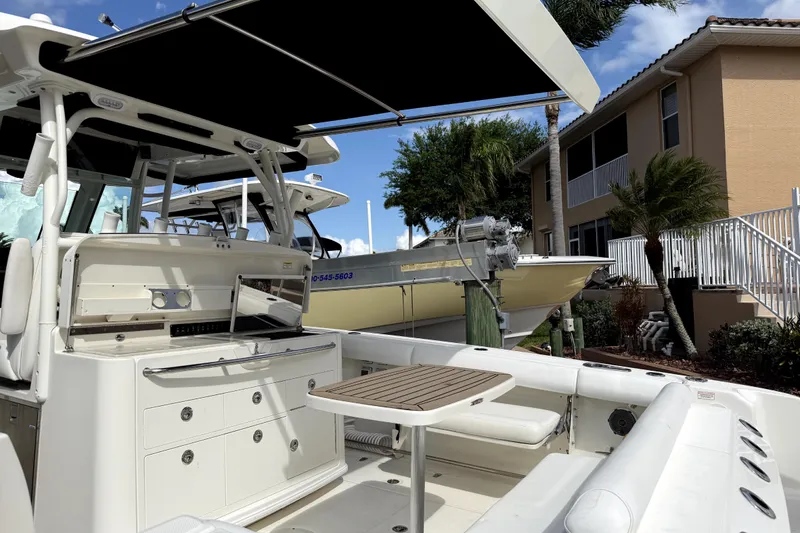 Slide: The Image of 2014 Boston Whaler 350 Outrage boat with seating and table, docked near a house. - 61