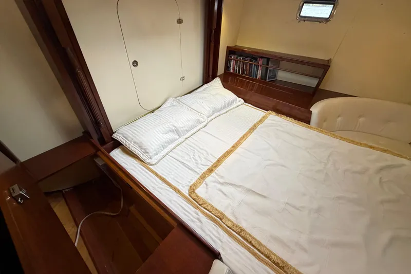 Slide: The Image of Luxurious cabin interior of 2011 Custom Build 50' Ketch, featuring a cozy bed and bookshelf. - 49