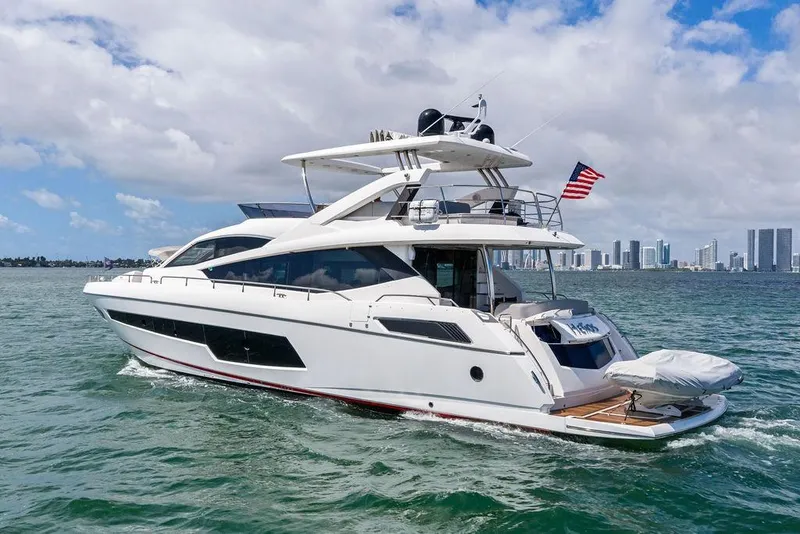 Slide: The Image of 2018 Sunseeker 75 Sport Yacht cruising on water with city skyline in background. - 13
