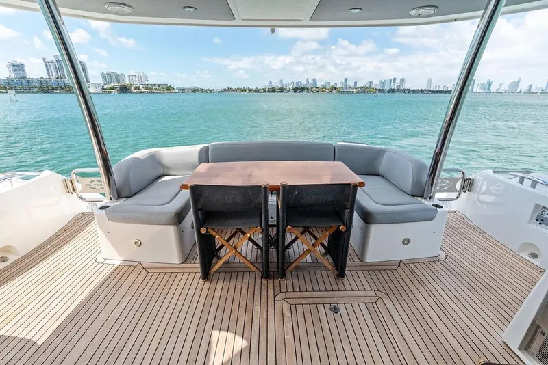 Slide: The Image of Luxurious Sunseeker 75 Sport Yacht deck with seating, overlooking serene waters and city skyline. - 18