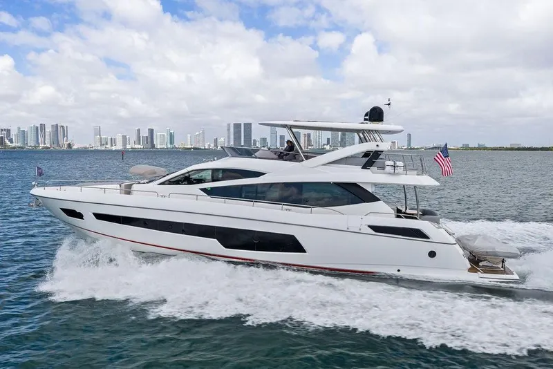 Slide: The Image of 2018 Sunseeker 75 Sport Yacht cruising on water with city skyline in background. - 2
