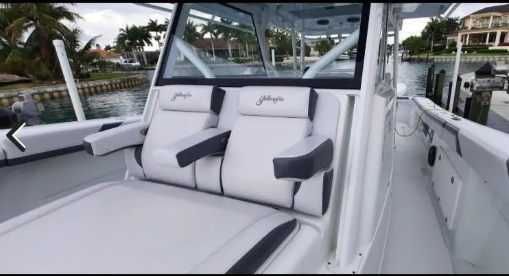 Slide: The Image of 2019 Yellowfin Center Console boat with cushioned seating, docked near palm trees. - 19