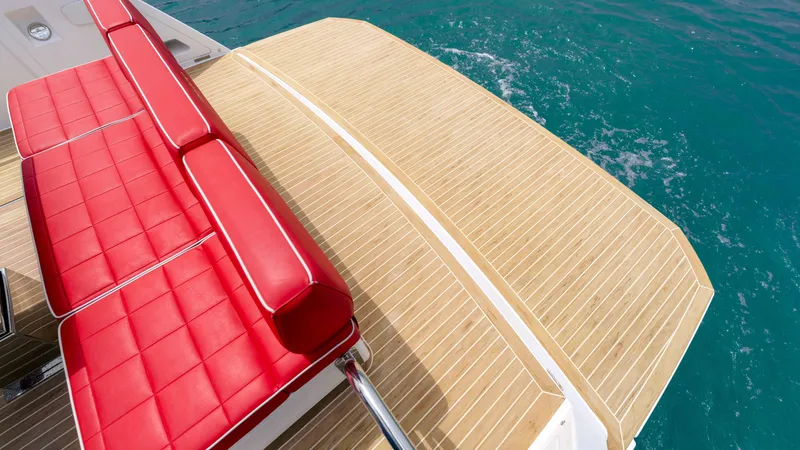 Slide: The Image of Pardo Yachts 38, 2023, featuring red seats and wooden deck by the sea. - 27