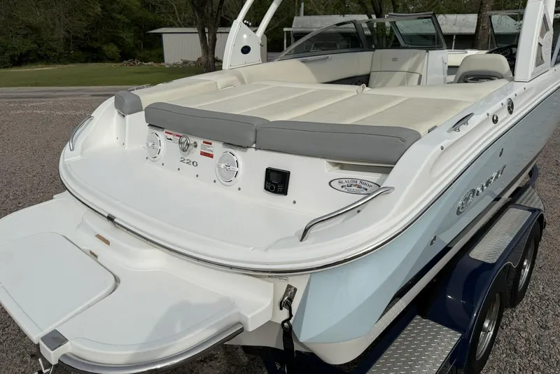 Slide: The Image of 2016 Cobalt 220 boat with white and gray seating, parked on a trailer. - 13