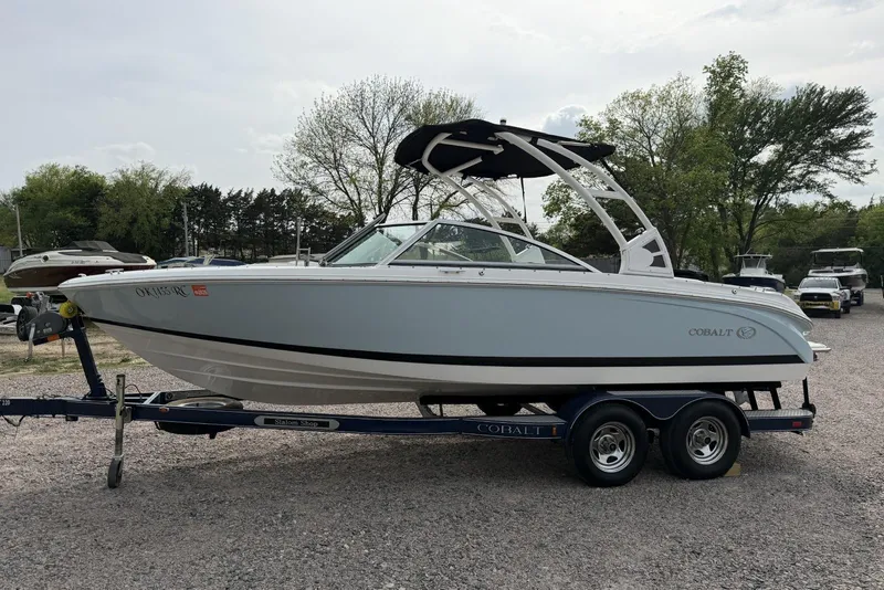 Slide: The Image of 2016 Cobalt 220 boat on trailer, parked outdoors with trees in background. - 5