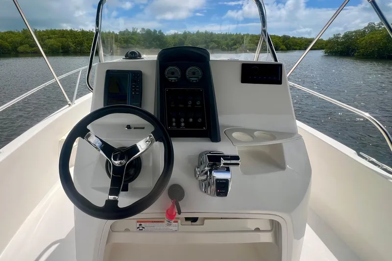 Slide: The Image of 2008 Boston Whaler 200 Dauntless boat helm with steering wheel and controls on a sunny day. - 4