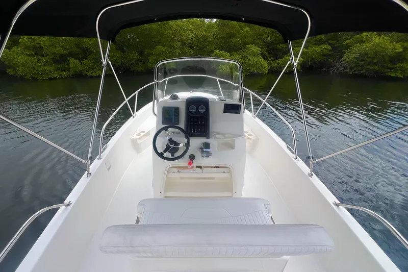 Slide: The Image of 2008 Boston Whaler 200 Dauntless boat interior with steering console, surrounded by calm water. - 7