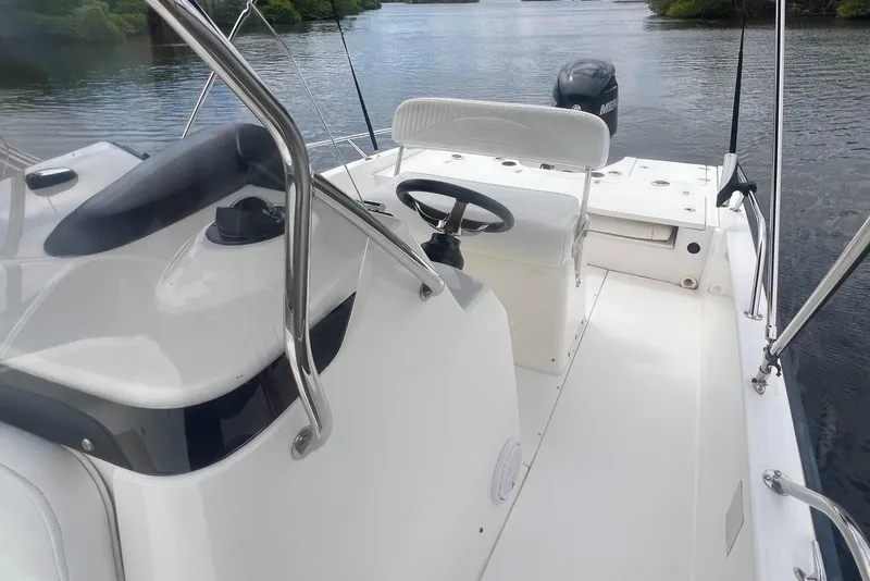 Slide: The Image of 2008 Boston Whaler 200 Dauntless boat interior with steering wheel and seating on calm water. - 8