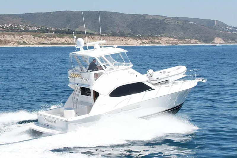 The Image of 2003 Riviera 40 Flybridge yacht cruising on ocean near scenic coastline. - 0