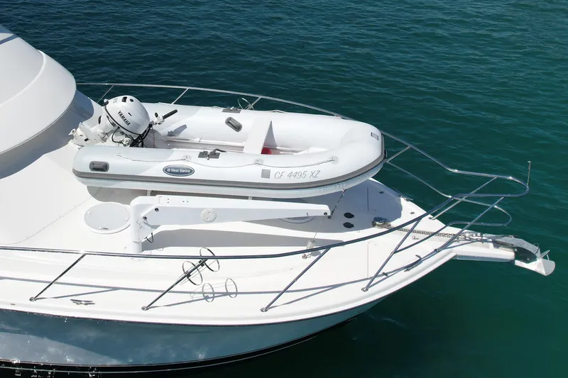 Slide: The Image of 2003 Riviera 40 Flybridge yacht with inflatable dinghy on deck, floating on clear blue water. - 12