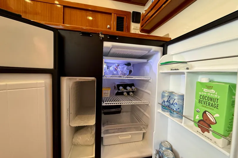 Slide: The Image of Open refrigerator on 2003 Riviera 40 Flybridge yacht, stocked with beverages and food items. - 33