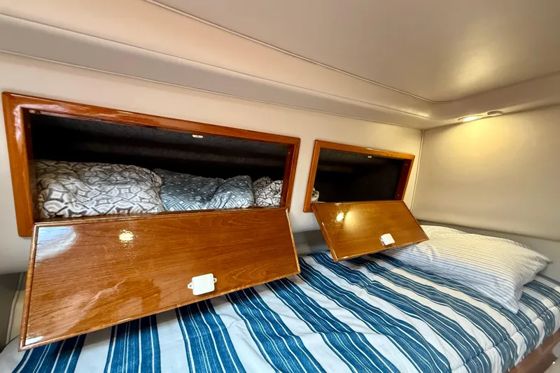 Slide: The Image of Cozy cabin interior of 2003 Riviera 40 Flybridge with striped bedding and wooden storage. - 51
