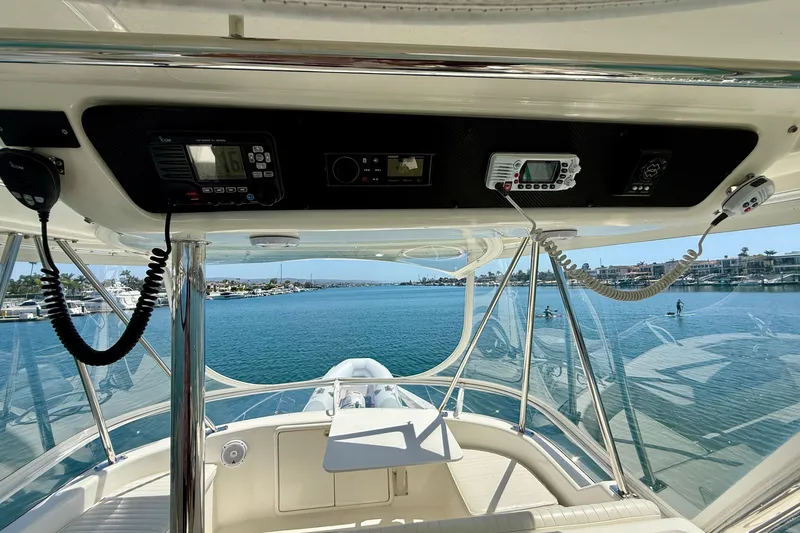 Slide: The Image of 2003 Riviera 40 Flybridge yacht interior with navigation equipment, overlooking serene waterfront view. - 53