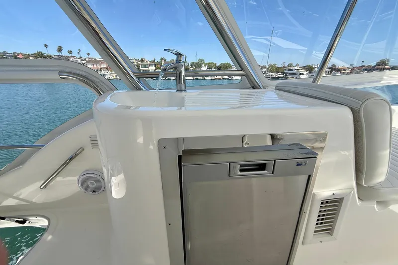 Slide: The Image of 2003 Riviera 40 Flybridge yacht interior with sink and mini fridge, overlooking marina. - 62