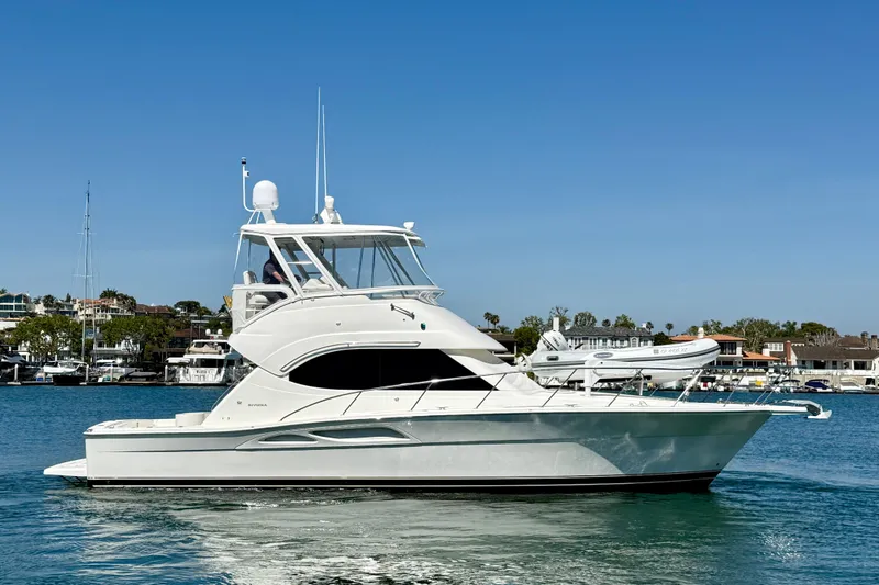 Slide: The Image of 2003 Riviera 40 Flybridge yacht cruising on a sunny day in a marina. - 7