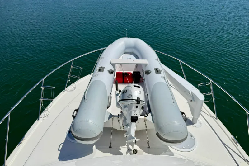 Slide: The Image of 2003 Riviera 40 Flybridge yacht with inflatable boat on deck, floating on calm water. - 74