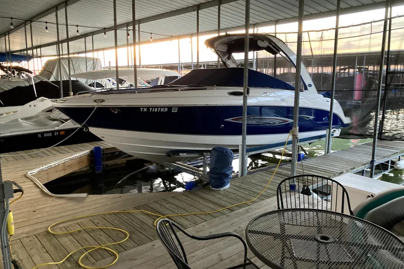 The Image of 2005 Chaparral 256 SSi boat docked in a covered marina, surrounded by other vessels. - 0