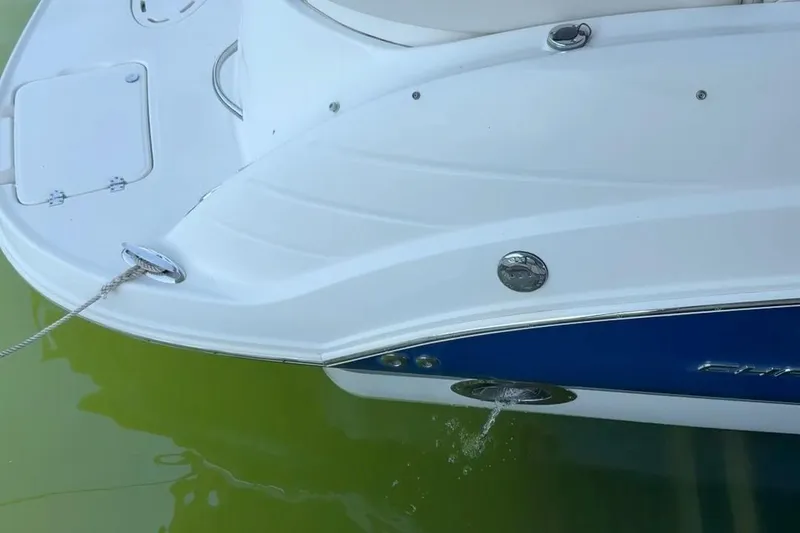 Slide: The Image of 2005 Chaparral 256 SSi boat stern with water drainage, docked on green water. - 6