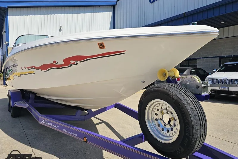Slide: The Image of 2001 Powerquest 280 Silencer boat on trailer, vibrant graphics, parked outside a building. - 11
