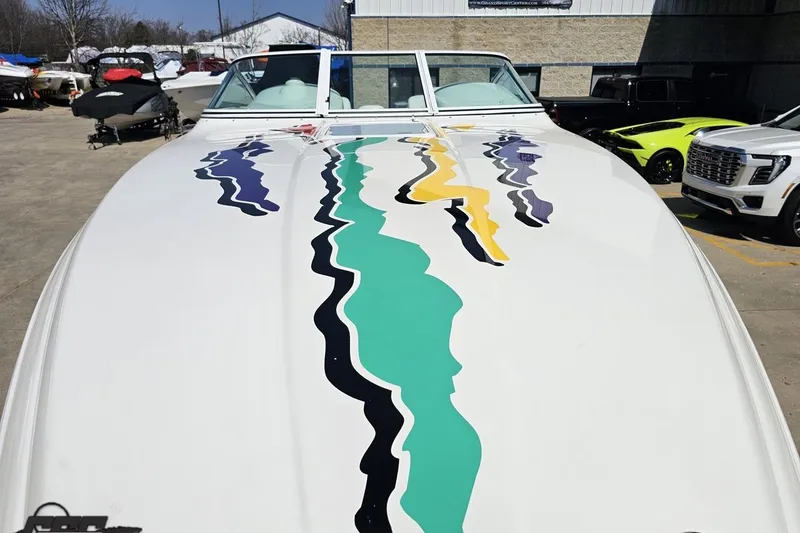 Slide: The Image of 2001 Powerquest 280 Silencer boat with colorful abstract graphics on deck, parked outdoors. - 13