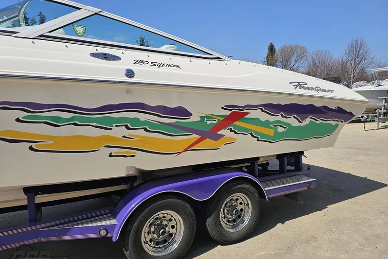 Slide: The Image of 2001 Powerquest 280 Silencer boat with colorful graphics on a purple trailer. - 20
