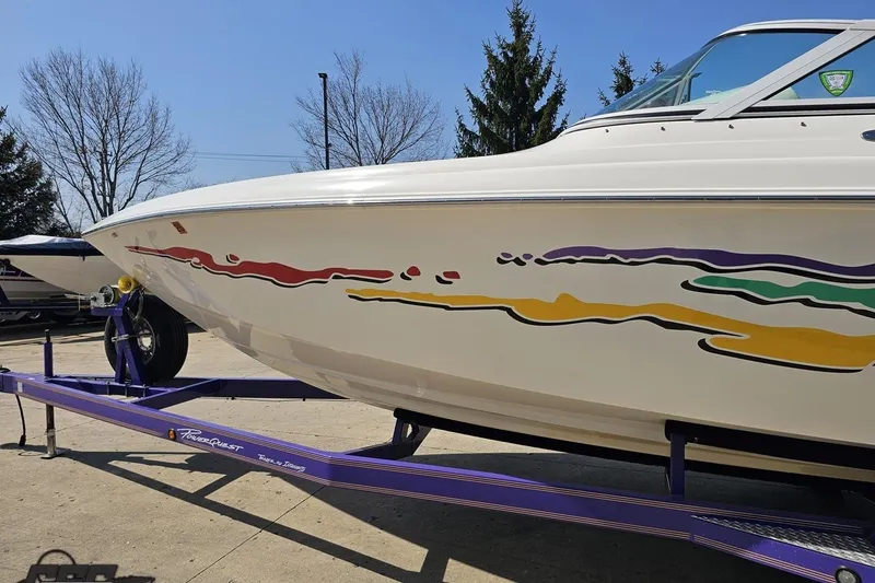 Slide: The Image of 2001 Powerquest 280 Silencer boat on trailer with colorful graphics, parked outdoors. - 21