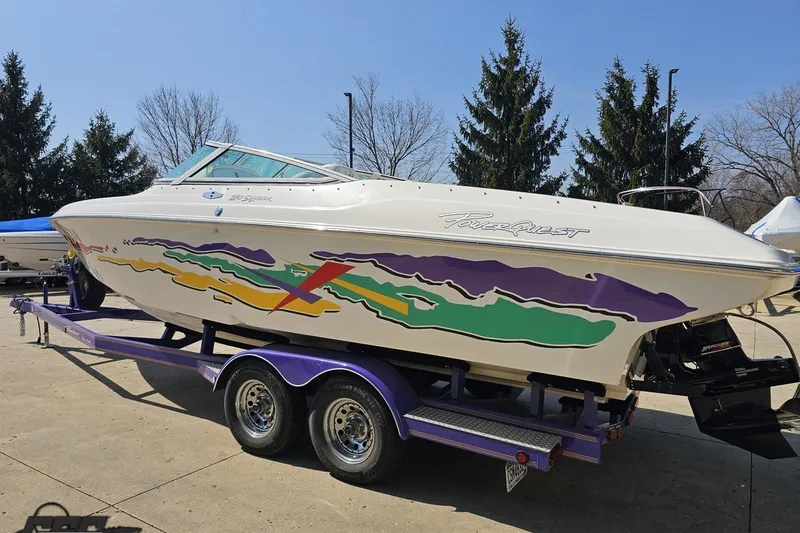 Slide: The Image of 2001 Powerquest 280 Silencer boat on trailer with colorful graphics, parked outdoors. - 23
