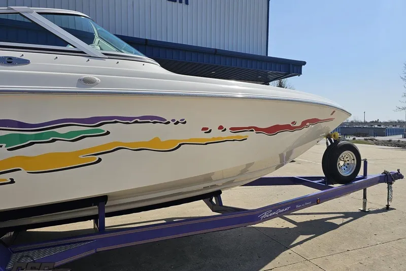 Slide: The Image of 2001 Powerquest 280 Silencer boat on trailer with colorful graphics, parked outdoors. - 4