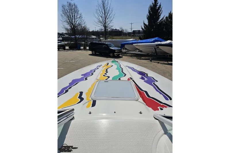 Slide: The Image of 2001 Powerquest 280 Silencer boat with colorful graphics on deck, parked outdoors. - 56