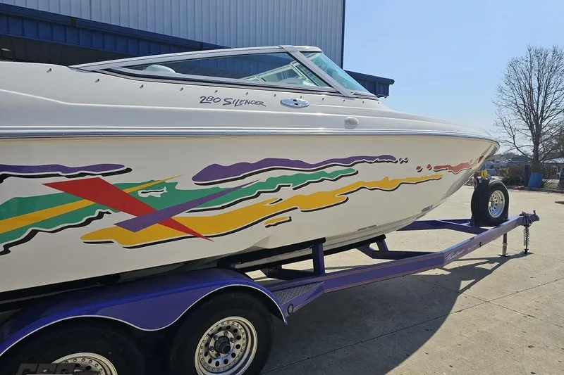 Slide: The Image of 2001 Powerquest 280 Silencer boat with colorful graphics on a trailer. - 6