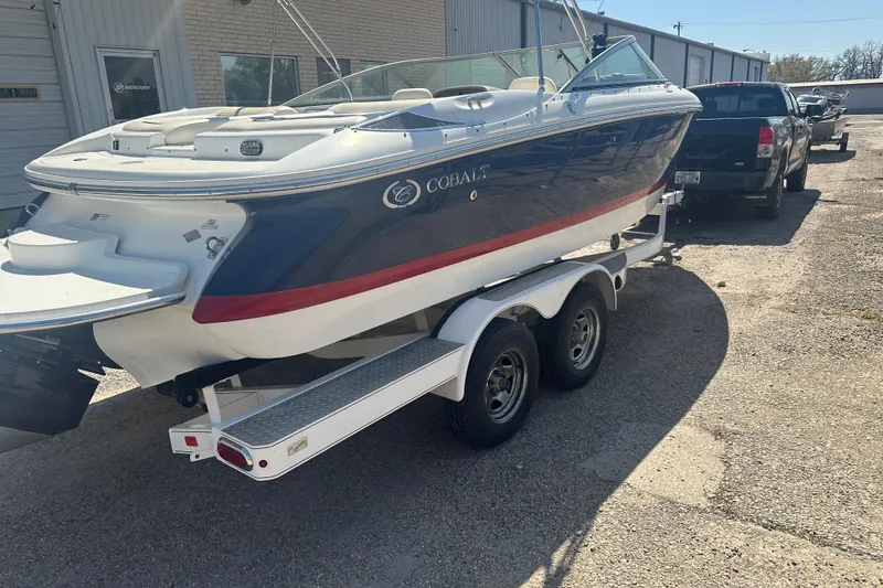 Slide: The Image of 2006 Cobalt 220S boat on trailer, parked outdoors near a building. - 13