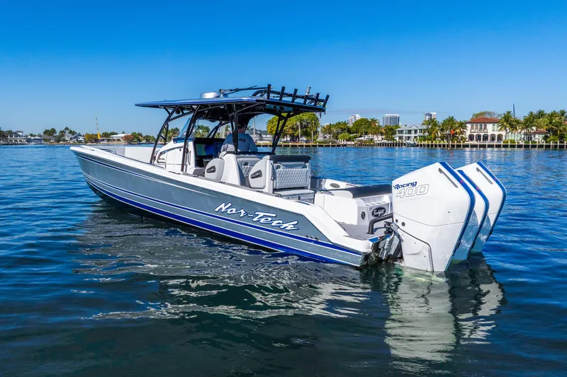 Slide: The Image of 2026 Nor-Tech 390 Sport Center Console boat on calm water, showcasing sleek design and powerful engines. - 13