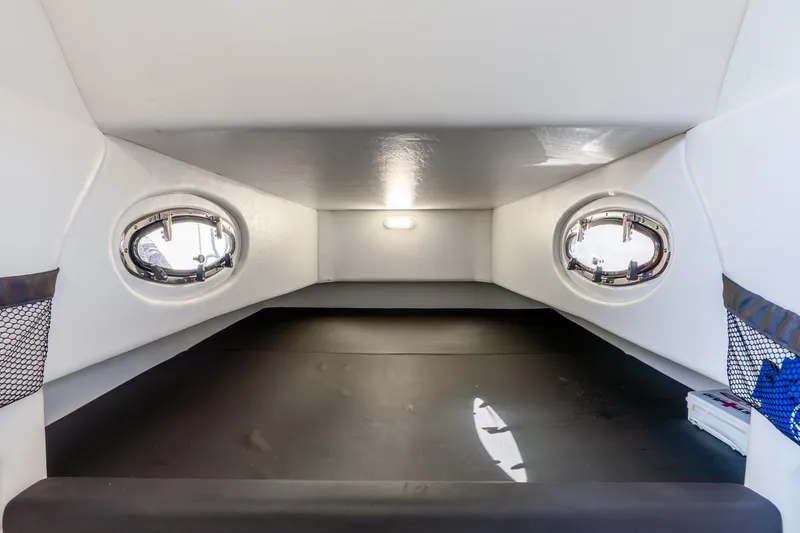 Slide: The Image of Interior cabin of 2026 Nor-Tech 390 Sport Center Console boat, featuring portholes and storage. - 48