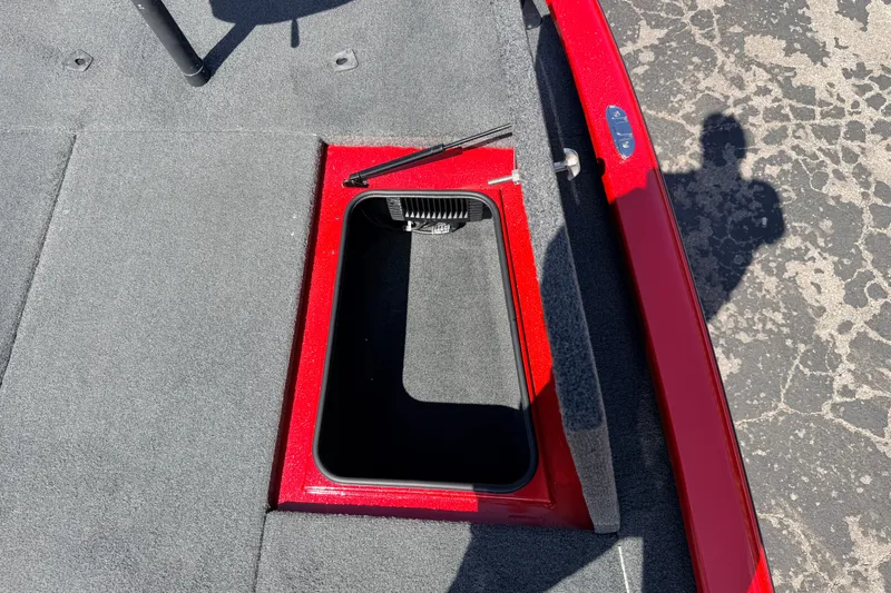 Slide: The Image of Open storage compartment on 2023 Avid 20 XB boat, featuring red trim and gray carpet. - 24