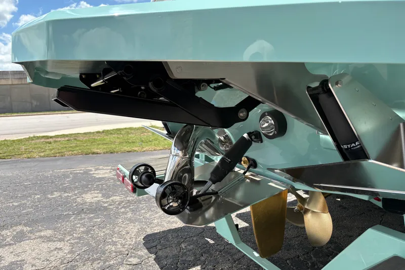 Slide: The Image of 2026 Supra SE 550 boat stern with propeller and trim tabs, parked on pavement. - 11