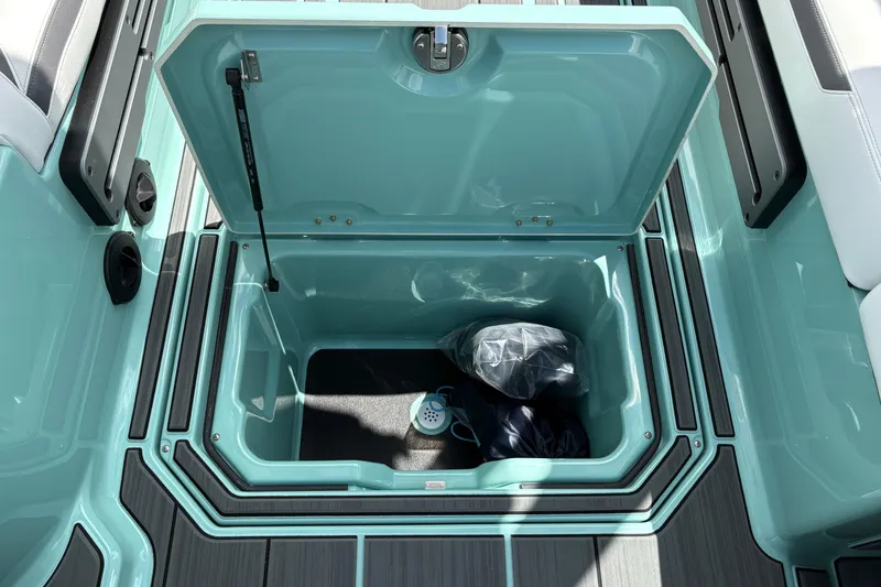Slide: The Image of Open storage compartment in 2026 Supra SE 550 boat, featuring teal interior and black accessories. - 27