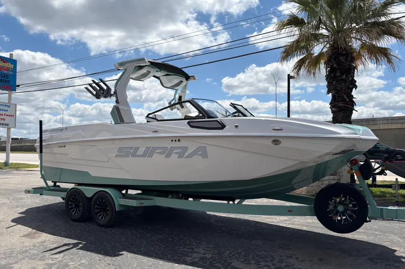 Slide: The Image of 2026 Supra SE 550 boat on trailer, parked outdoors under a partly cloudy sky. - 47
