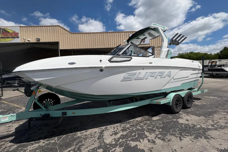 Slide: The Image of 2026 Supra SE 550 boat on trailer, parked outdoors under a partly cloudy sky. - 5