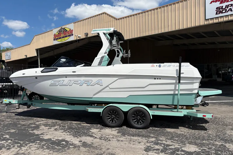 Slide: The Image of 2026 Supra SE 550 boat on trailer outside dealership under blue sky. - 6