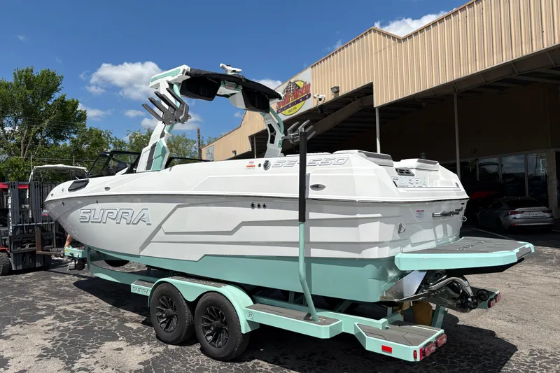 Slide: The Image of 2026 Supra SE 550 boat on trailer, parked outside a building under a clear sky. - 7