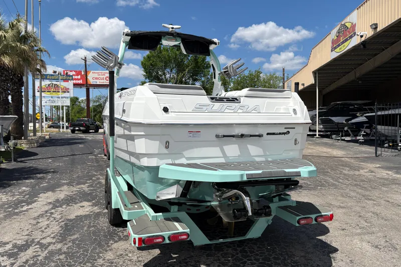 Slide: The Image of 2026 Supra SE 550 boat on trailer, parked outside dealership under blue sky. - 8