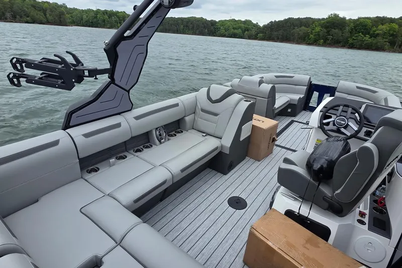 Slide: The Image of 2026 Montara Surf Boss EVO SLDH 25' boat interior with gray seating on a lake. - 2