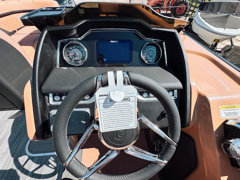 Slide: The Image of 2025 Godfrey AquaPatio Tritoon dashboard with steering wheel and control panel. - 13