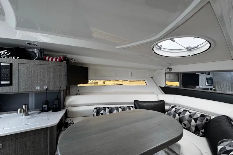 Slide: The Image of Interior of 2022 Monterey 295 Sport Yacht with modern seating, table, and kitchenette. - 27