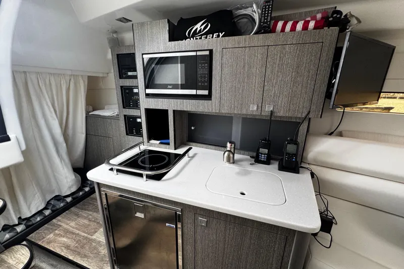 Slide: The Image of Modern kitchenette in 2022 Monterey 295 Sport Yacht with microwave, stove, and sink. - 28