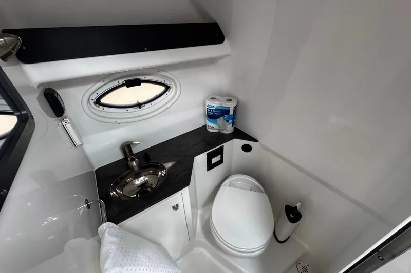 Slide: The Image of 2022 Monterey 295 Sport Yacht bathroom with sink, toilet, and porthole window. - 32